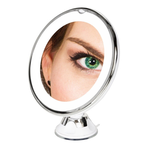 A close-up of a green eye reflected in a round magnifying vanity mirror on a stand.