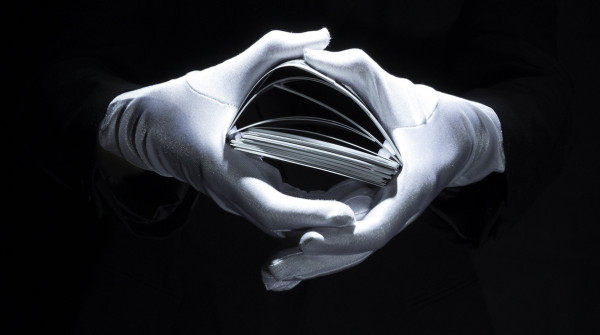 Magician's hand wearing white glove holding playing cards stack