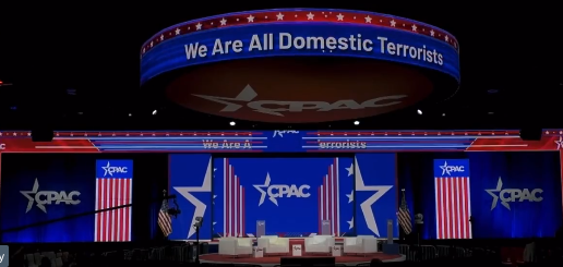Picture from the CPAC 2022 webcast with a banner that reads "We Are All Domestic Terrorist"