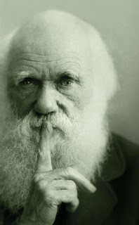 Photo of Charles Darwin with his index finger to his lips, “shhhhhhh.”