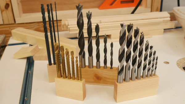 Wooden blocks with equally-spaced holes for storing various drill bits.